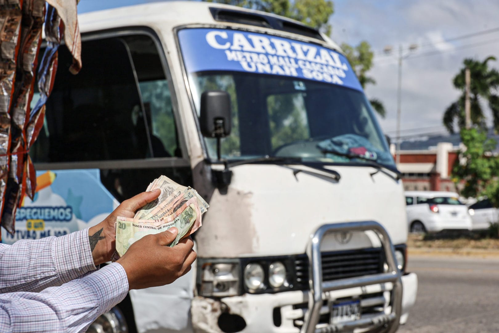 cobrador de transporte urbano contando dinero frente a bus